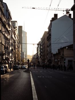 Silhouetted city street at sunset with a modern skyscraper in the background.