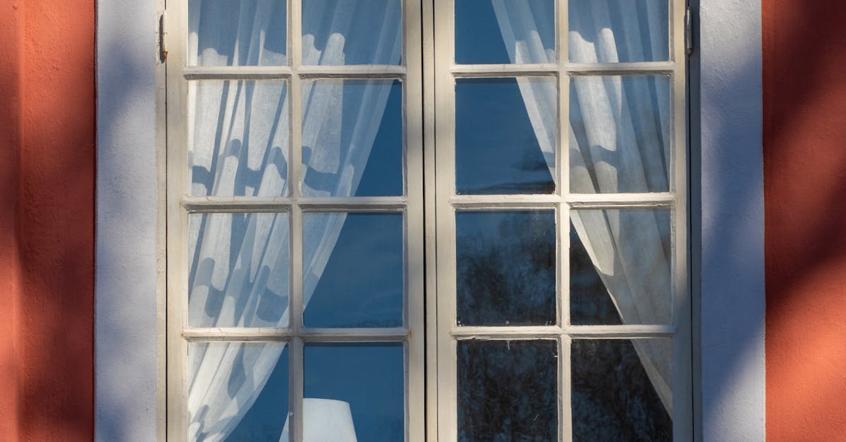 Charming traditional window with white curtains on orange wall reflecting sunlight in Jönköping, Sweden.