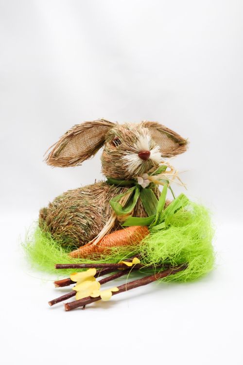 Free A charming straw rabbit figurine with a carrot and green grass accents, perfect for seasonal decor. Stock Photo