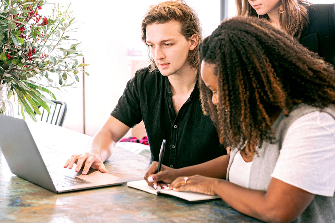 Man Aan Het Werk Op Laptop Terwijl Vrouw Notities Maakt