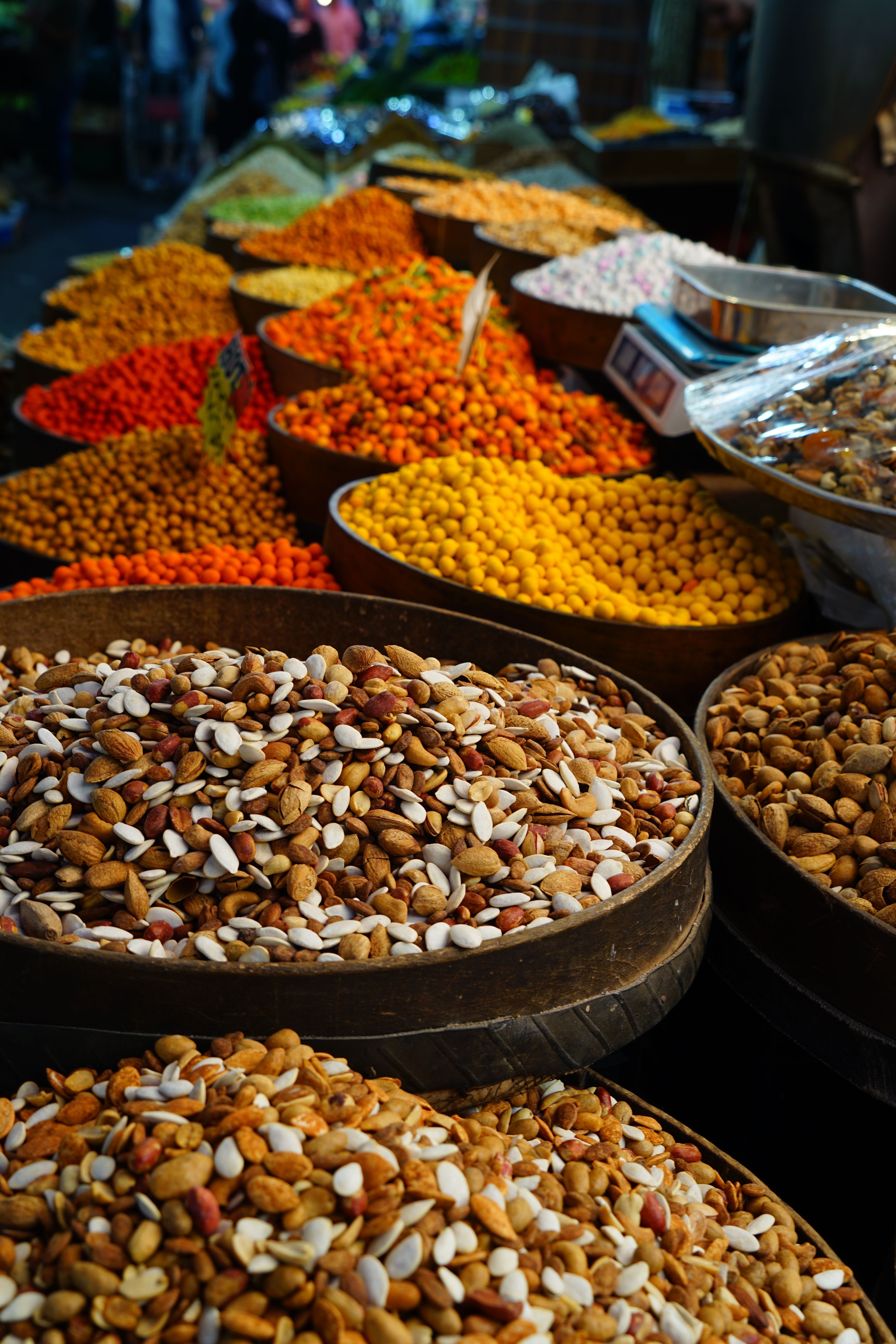 Free Vibrant display of various spices and nuts in large bowls at an outdoor market. Stock Photo