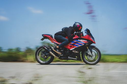 Free A motorcyclist on a red sports bike speeding down a deserted highway, showcasing motion and speed. Stock Photo
