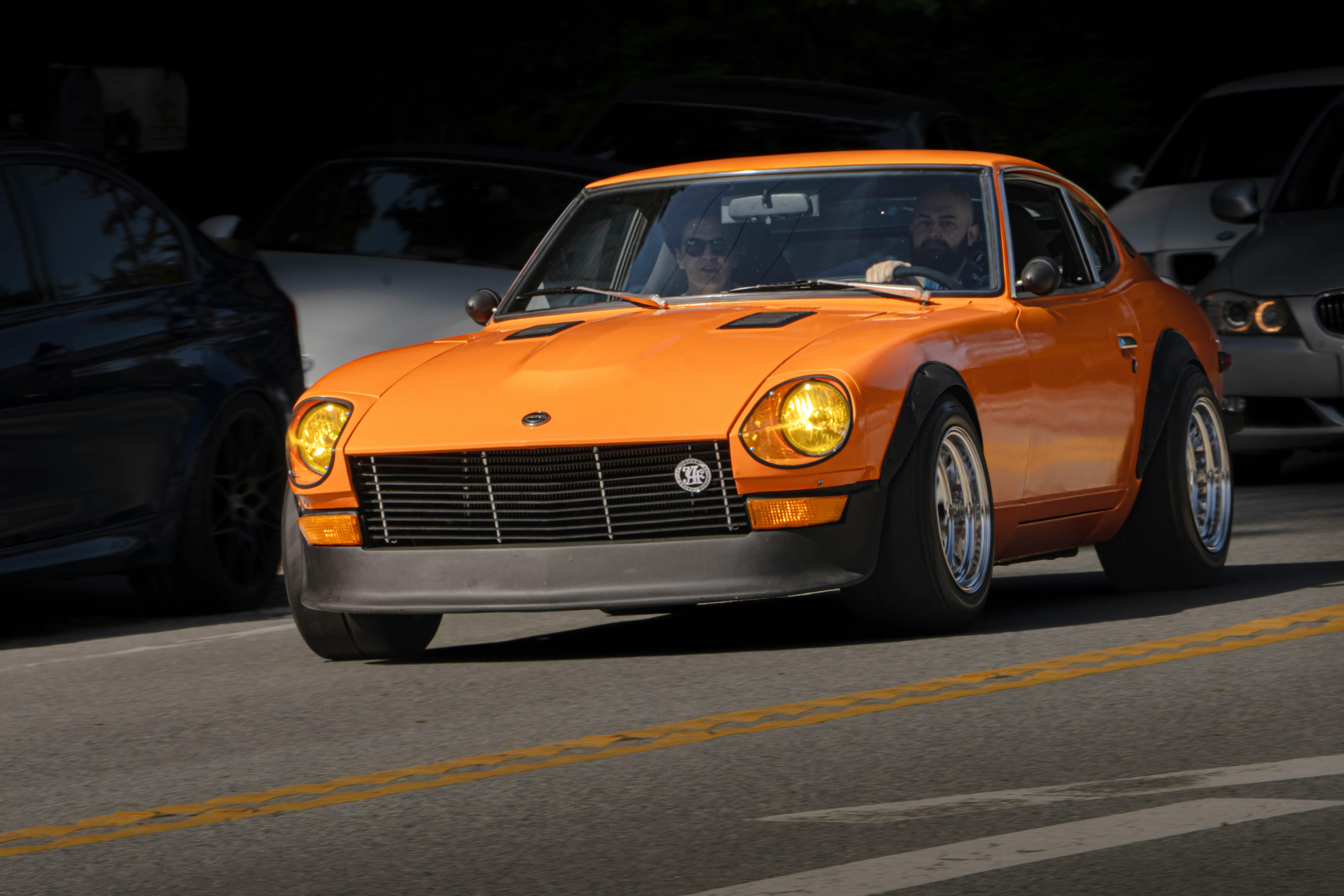 Vintage orange car driving on a sunny street in Saratoga, CA. Perfect for car enthusiasts and nostalgic automotive themes.