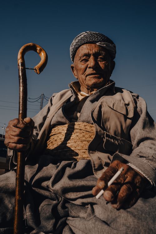 Free Portrait of an elderly Kurdish man with a walking stick and cigarette, showcasing traditional clothing and wisdom. Stock Photo