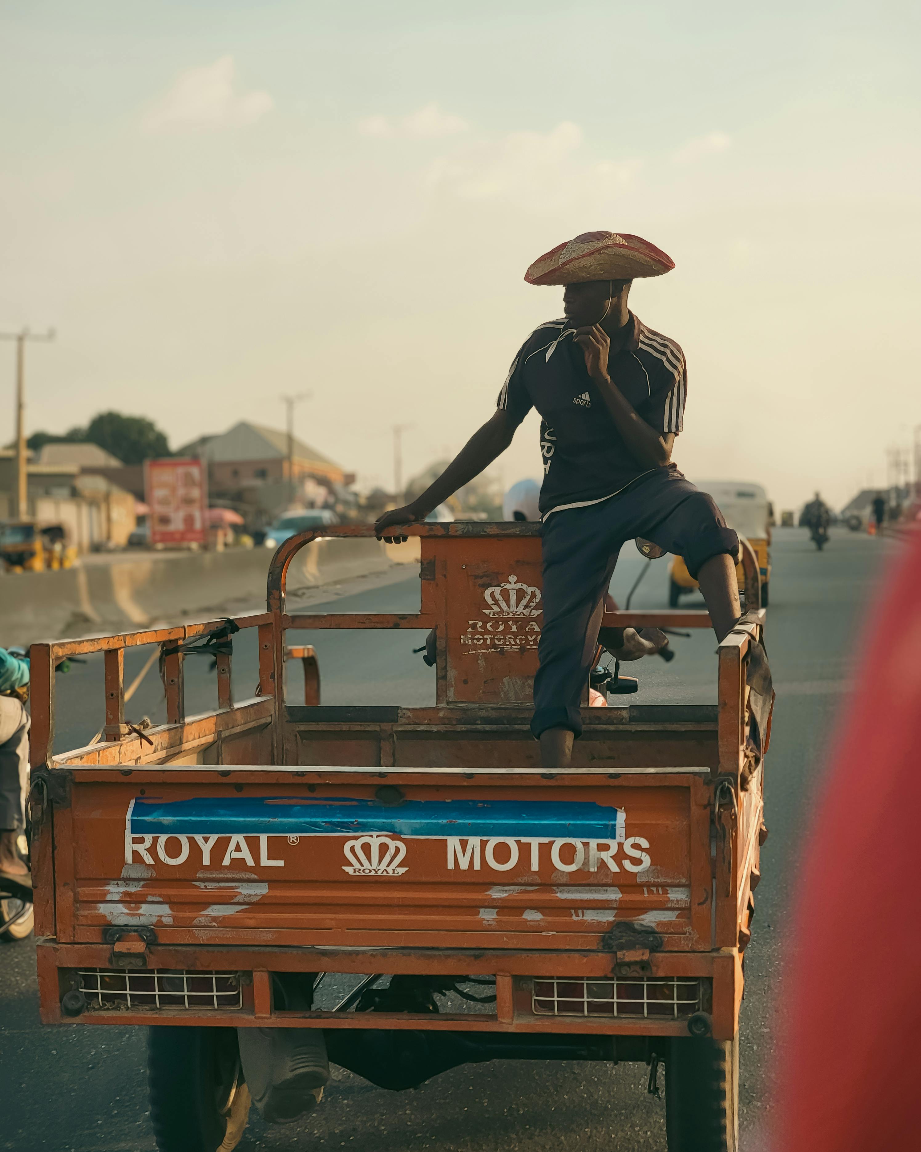 A man sitting on a cargo tricycle in a busy urban road during the daytime.