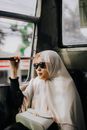 一位优雅的女人在雅加达的公共汽车上，戴着头巾和太阳镜旅行