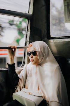 一位优雅的女人在雅加达的公共汽车上，戴着头巾和太阳镜旅行