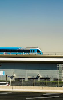Blue Dubai Metro train traveling on an elevated track in vibrant daylight.