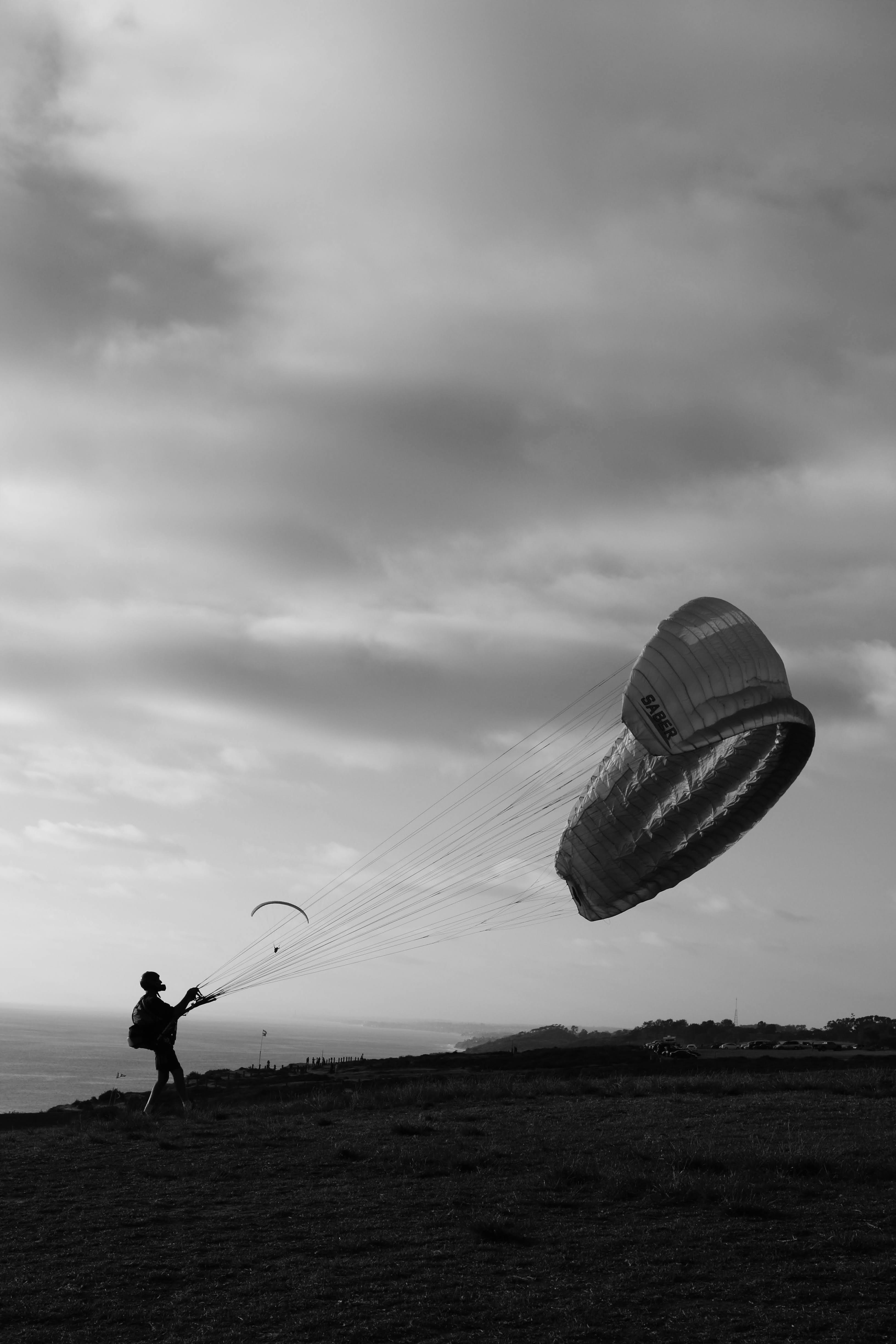 Silhouette of a paraglider preparing for takeoff in San Diego, capturing dynamic motion in black and white.