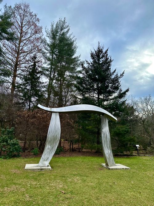 Free Elegant metallic sculpture amidst a serene forest backdrop, captured at dusk. Stock Photo
