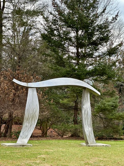 Free Sleek metal sculpture set in a tranquil forest setting, showcasing modern art. Stock Photo