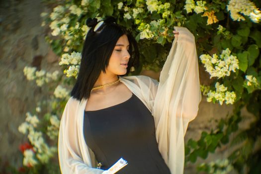 Stylish woman posing in a garden of white blossoms, showcasing elegance and nature.
