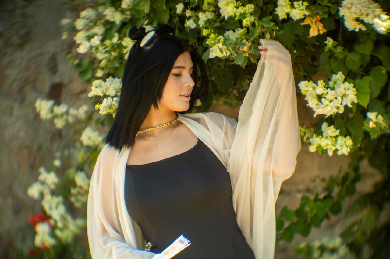 stylish woman posing in a garden of white blossoms showcasing elegance