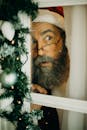 一个打扮成圣诞老人的大胡子男人透过室内的装饰窗户偷看