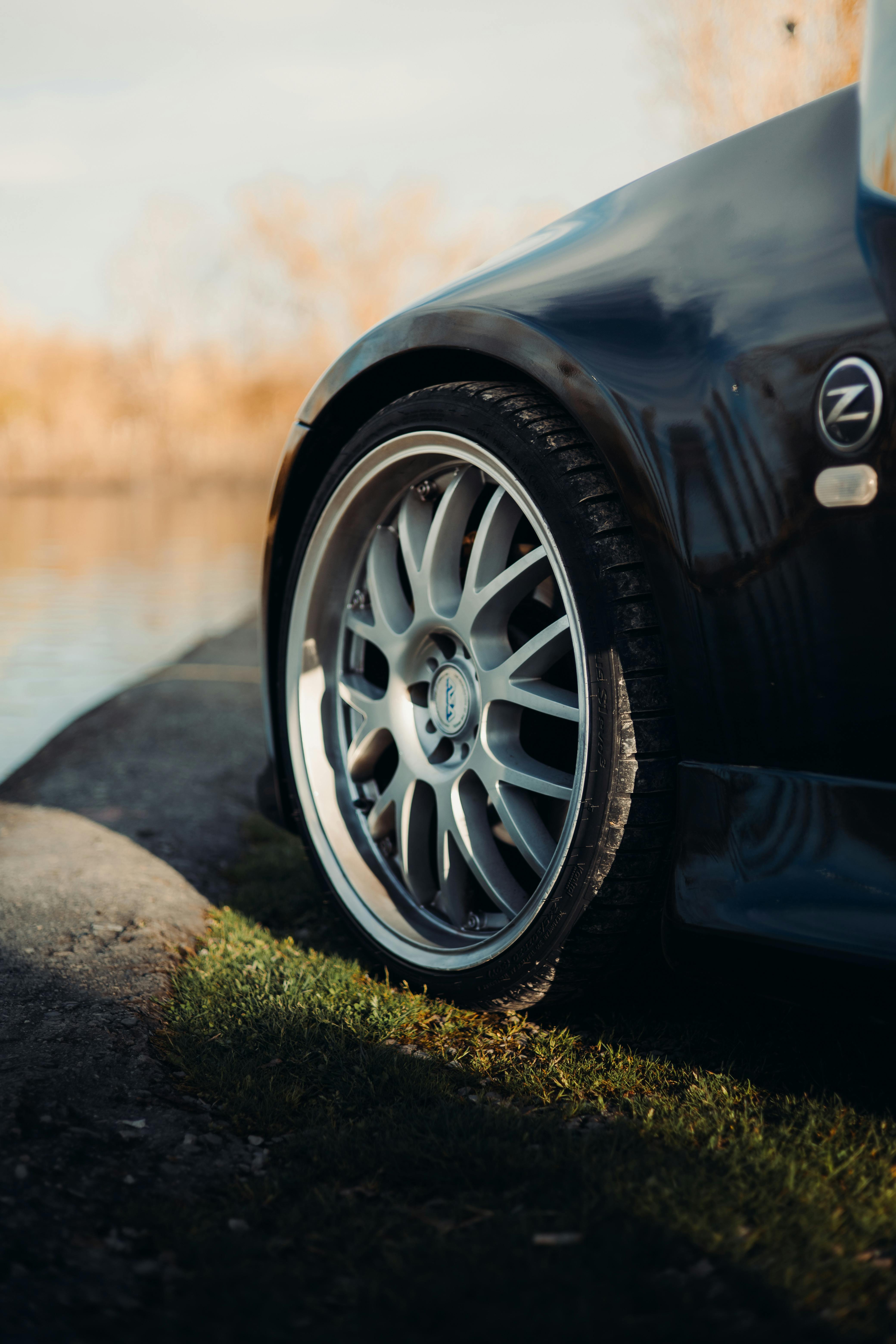 Detailed view of a sporty car's wheel beside a scenic water edge.