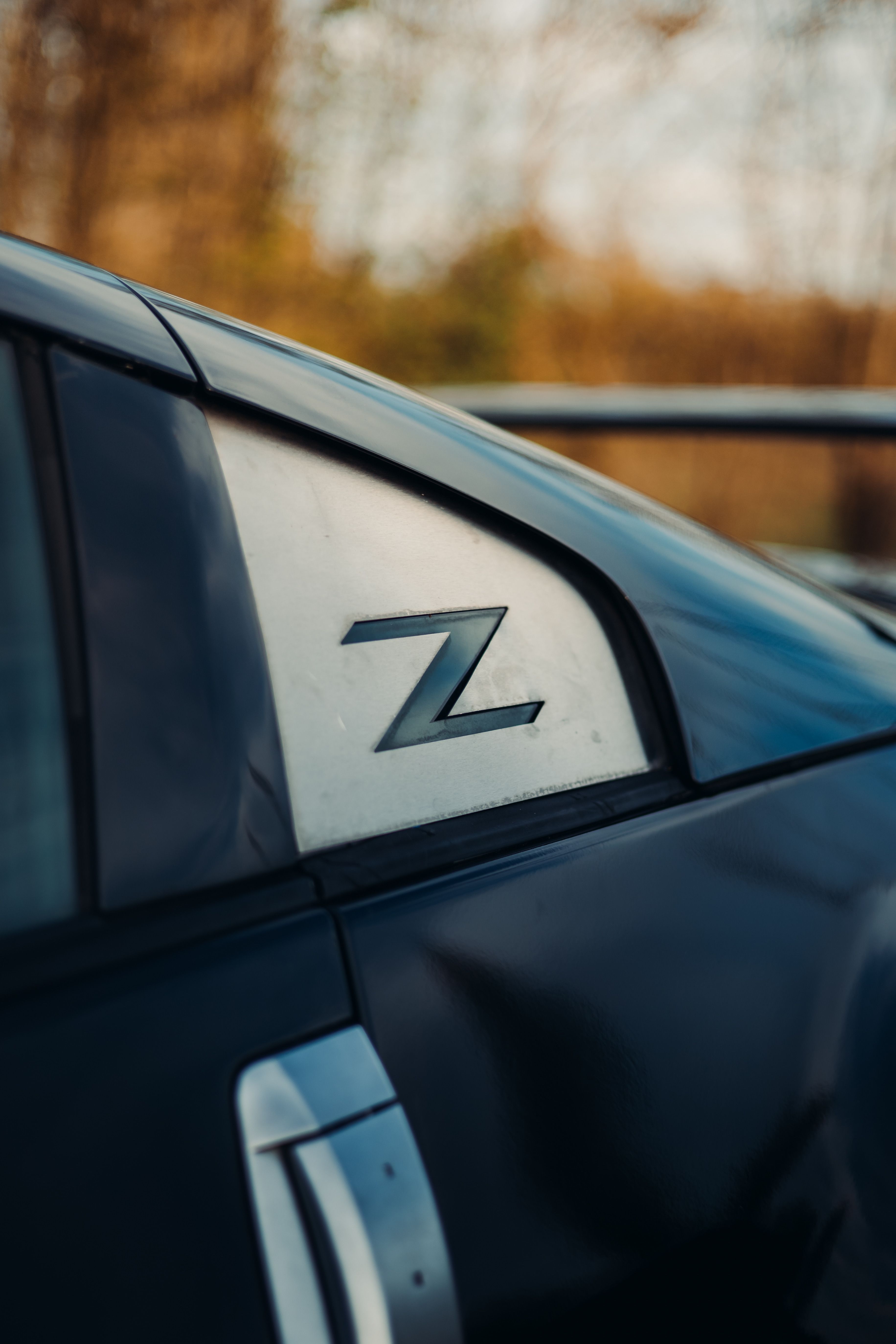 Detailed view of a black sports car's Z emblem, highlighting its sleek design.