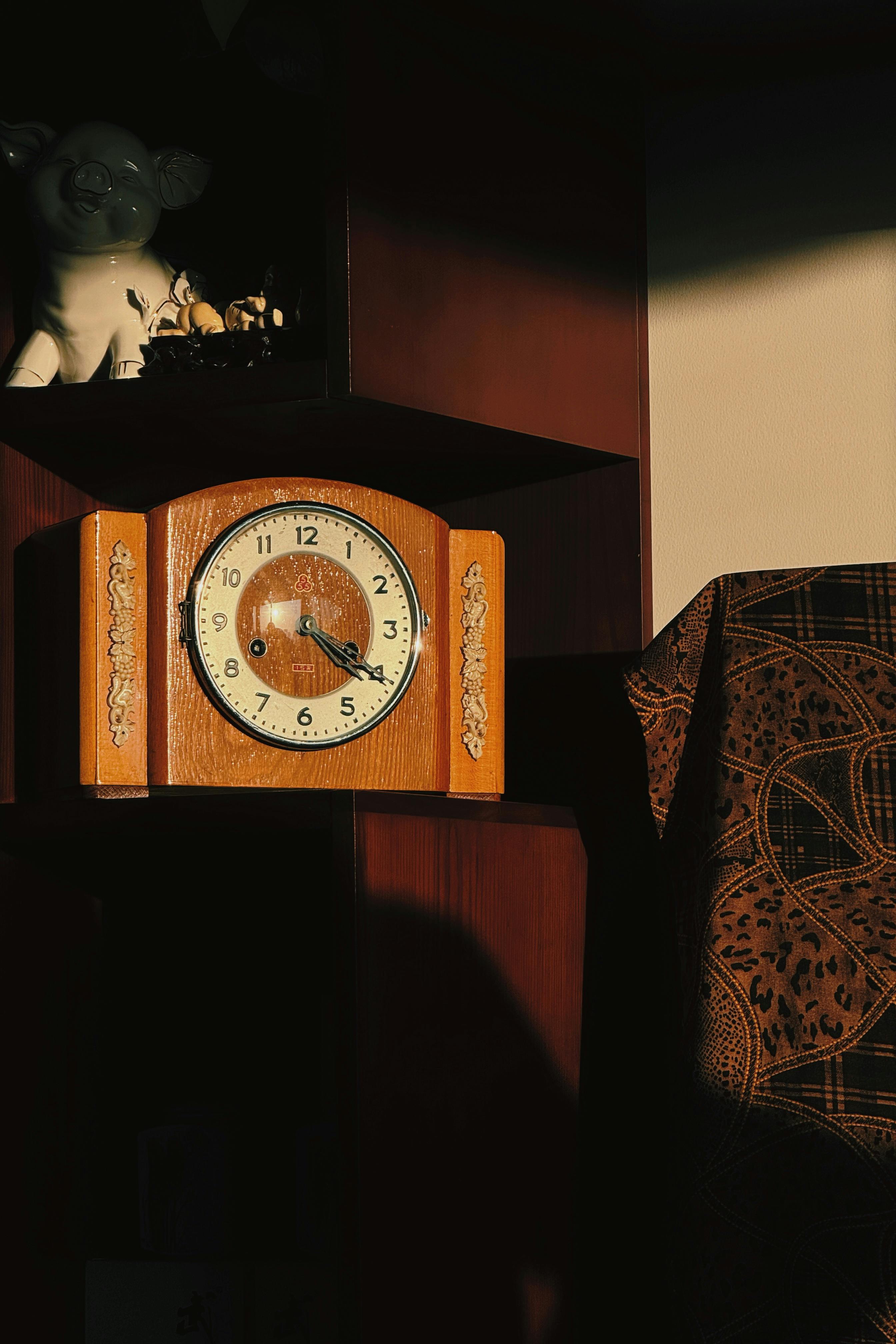 A classic wooden clock in warm sunlight casting shadows indoors.