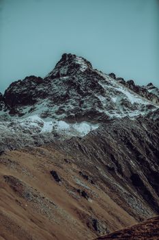 Majestic snow-covered mountain peak with rugged terrain against a clear sky.