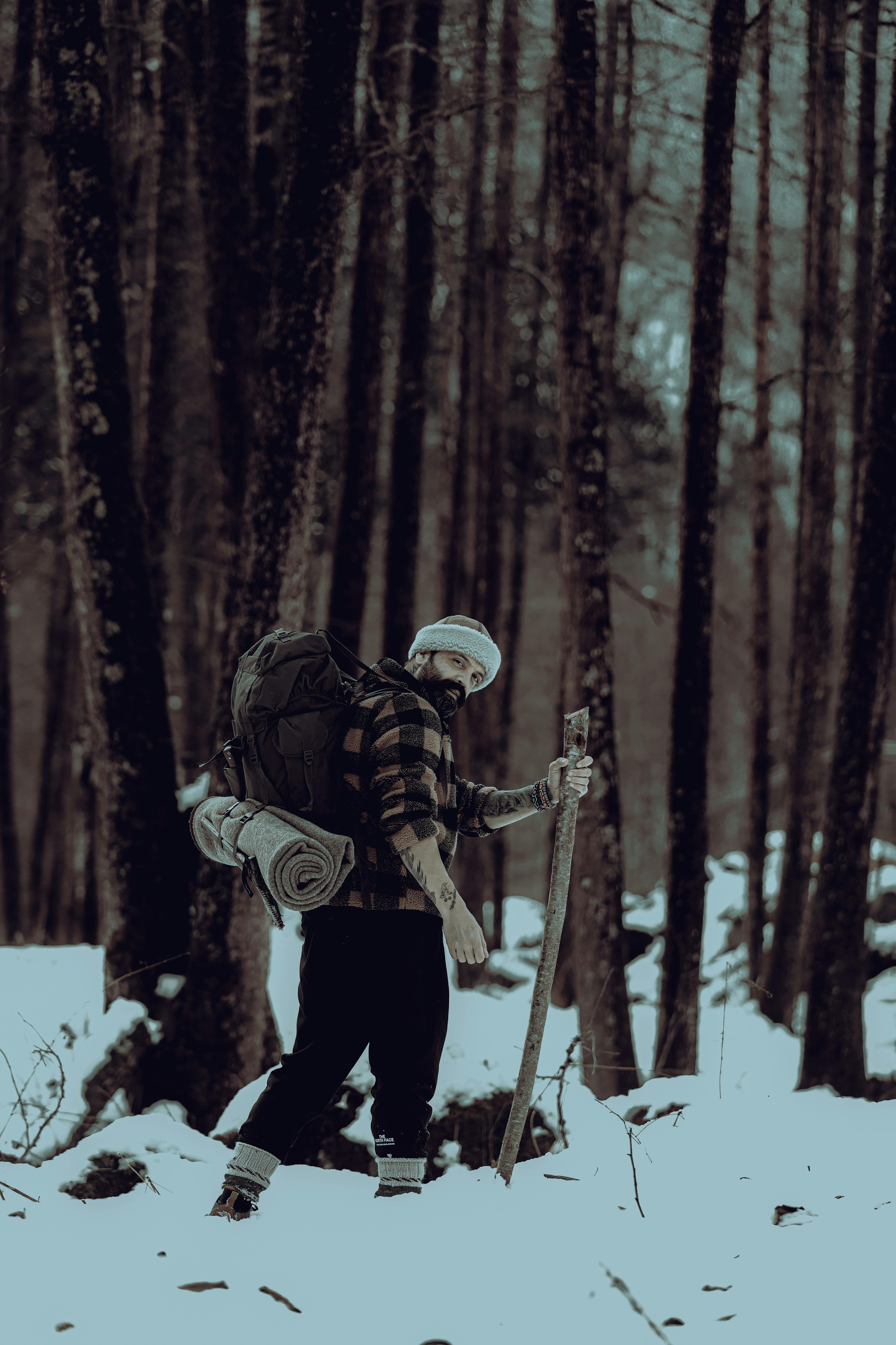 A lone hiker walks through a dense, snowy forest, showcasing winter adventure.