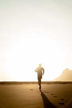 Silhouette of an adult running on the beach during sunrise, capturing the essence of solitude and adventure.