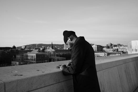 Black and white photo of a man in a beanie looking over Oslo's skyline.