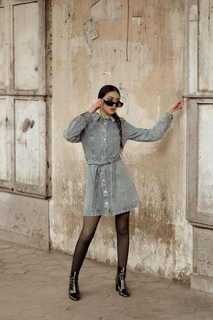 Stylish woman poses against rustic wall in Cairo, exuding urban chic fashion vibes.