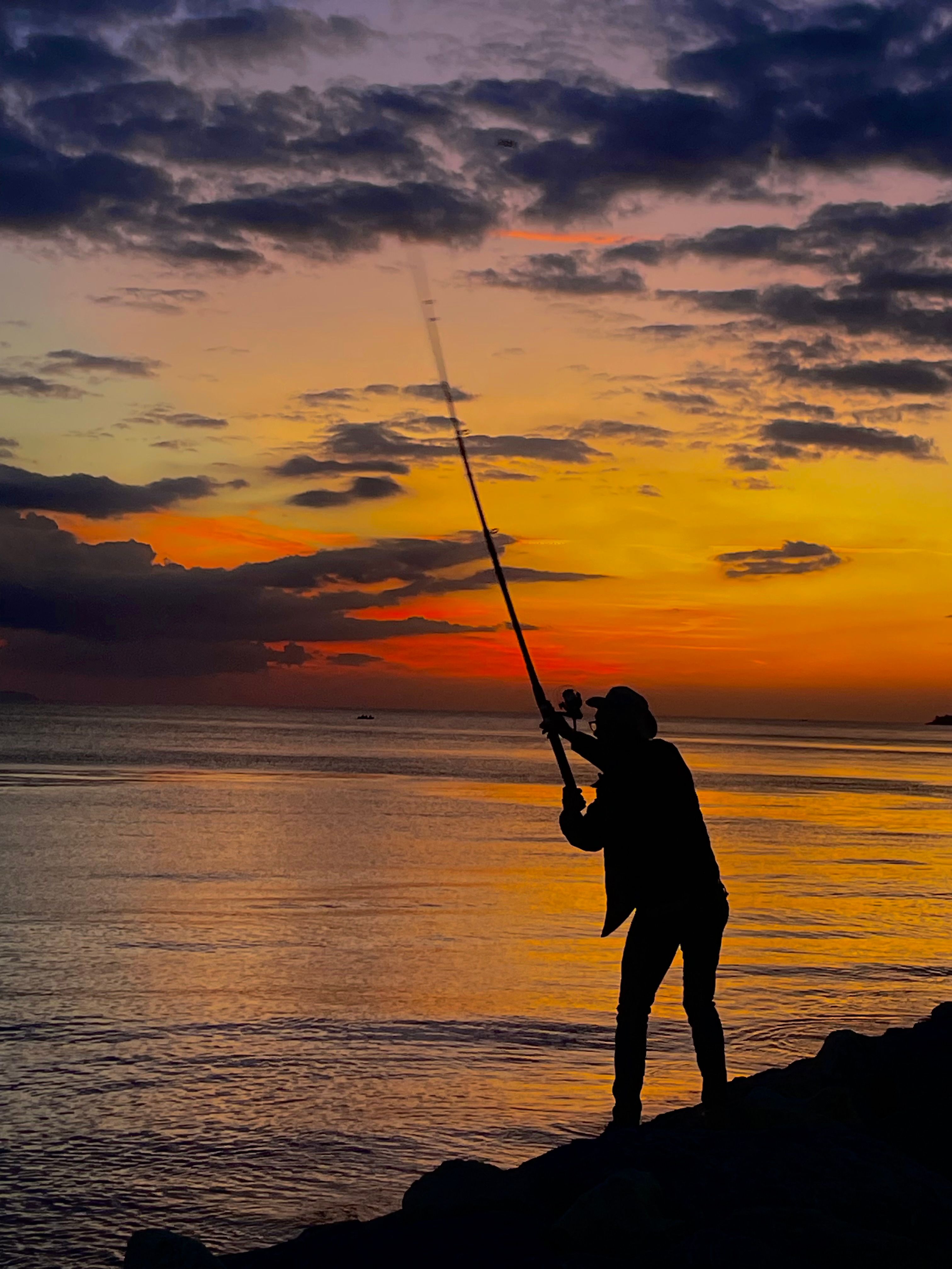 Silhouette of Fisherman at Sunset by the Sea · Free Stock Photo