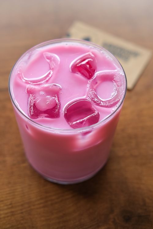 Free Top-down view of a vibrant pink iced drink with ice cubes, set on a wooden table. Stock Photo