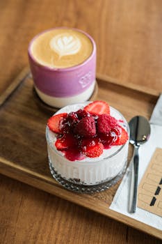 A delightful dessert topped with fresh berries paired with a cappuccino on a wooden tray.