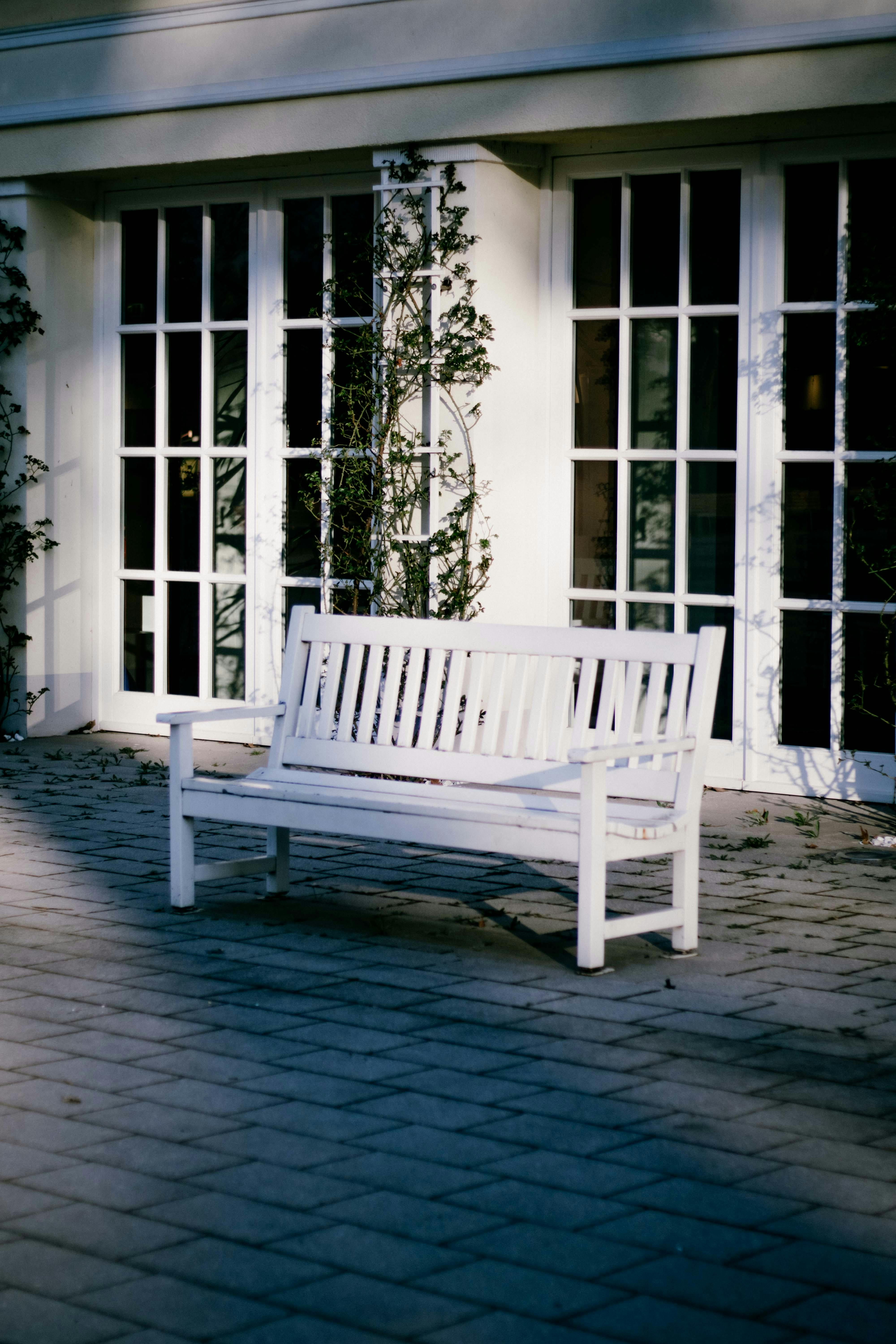 Gratuit O bancă albă liniștită pe fațada unei clădiri luminată de soare, perfectă pentru relaxare. Fotografie de stoc