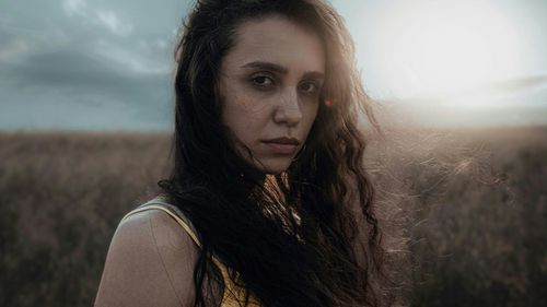 Free Evocative portrait of a woman in a field during sunset with a moody expression. Stock Photo