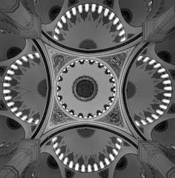Black and white image showcasing an intricately designed Islamic mosque ceiling with geometric patterns.