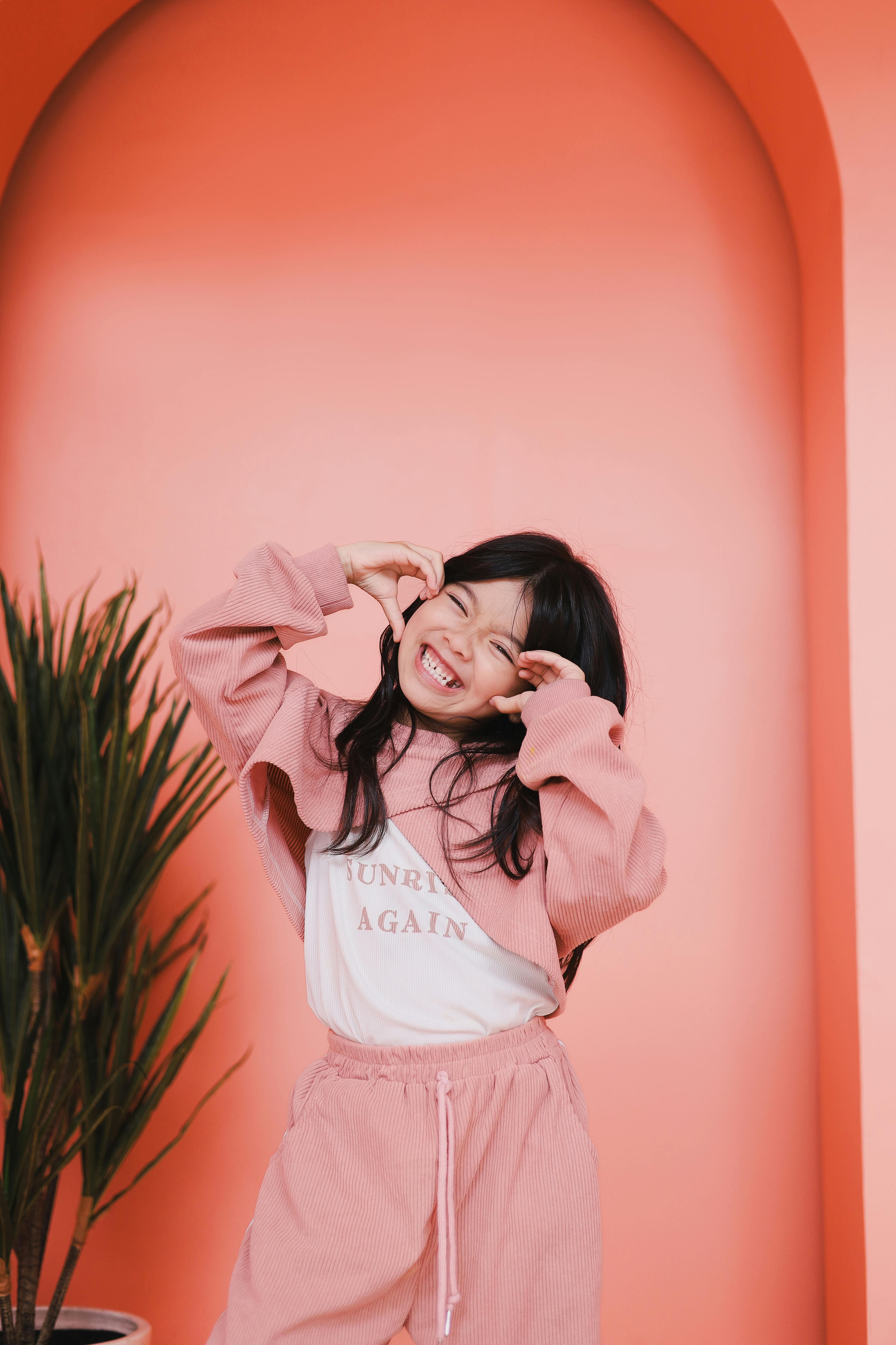 smiling child in pink by orange wall