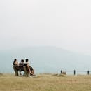 Three People Sitting on Brown Bench