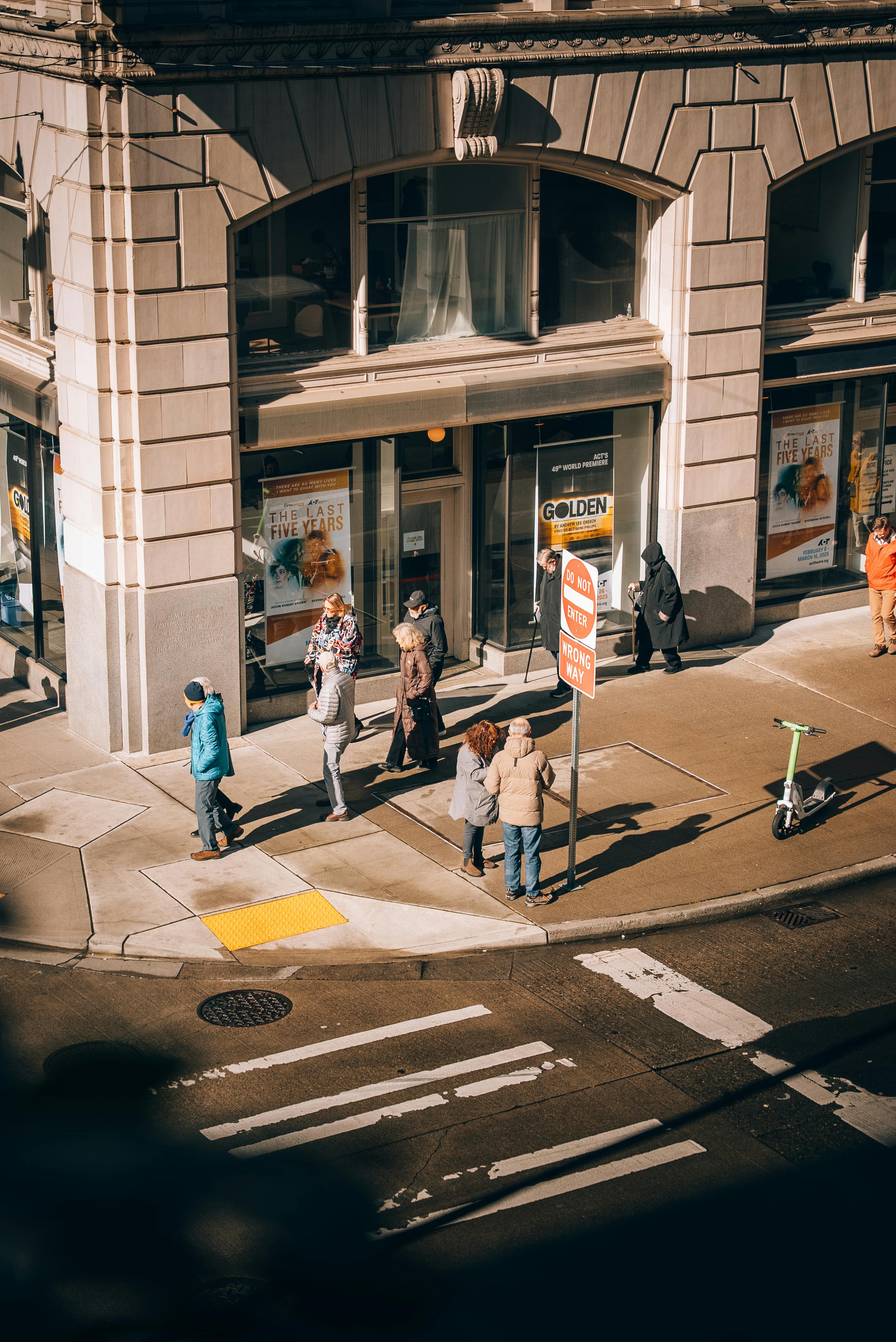 Urban scene of pedestrians at a Seattle street corner, captured from above.