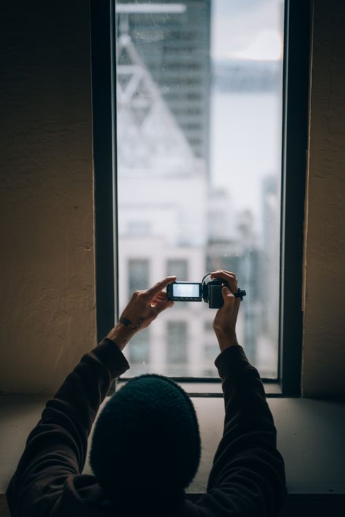 Free Person photographing Seattle skyline through a high-rise window. Stock Photo