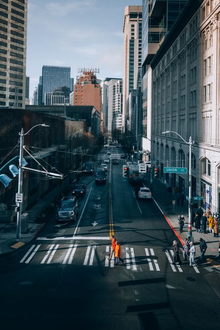 A dynamic street view of Seattle with pedestrians and vehicles on a busy city road during the day.