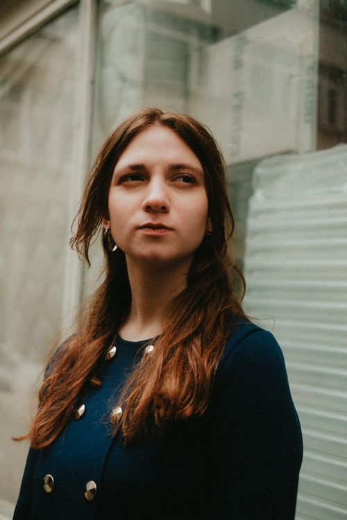 Free Portrait of a young woman looking off camera in an urban setting, wearing a blue outfit. Stock Photo
