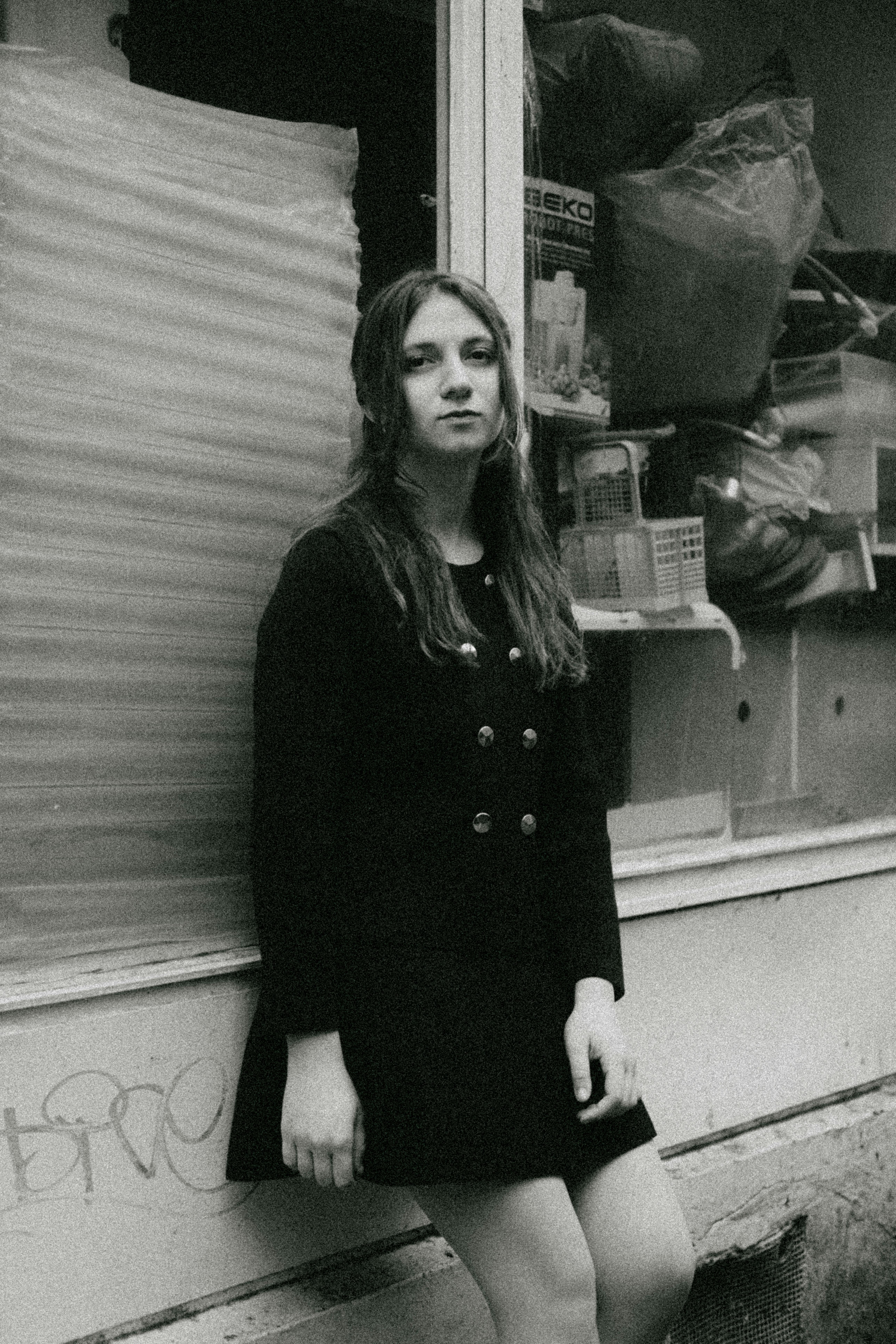 Black and white portrait of a woman in vintage clothing, standing outdoors.