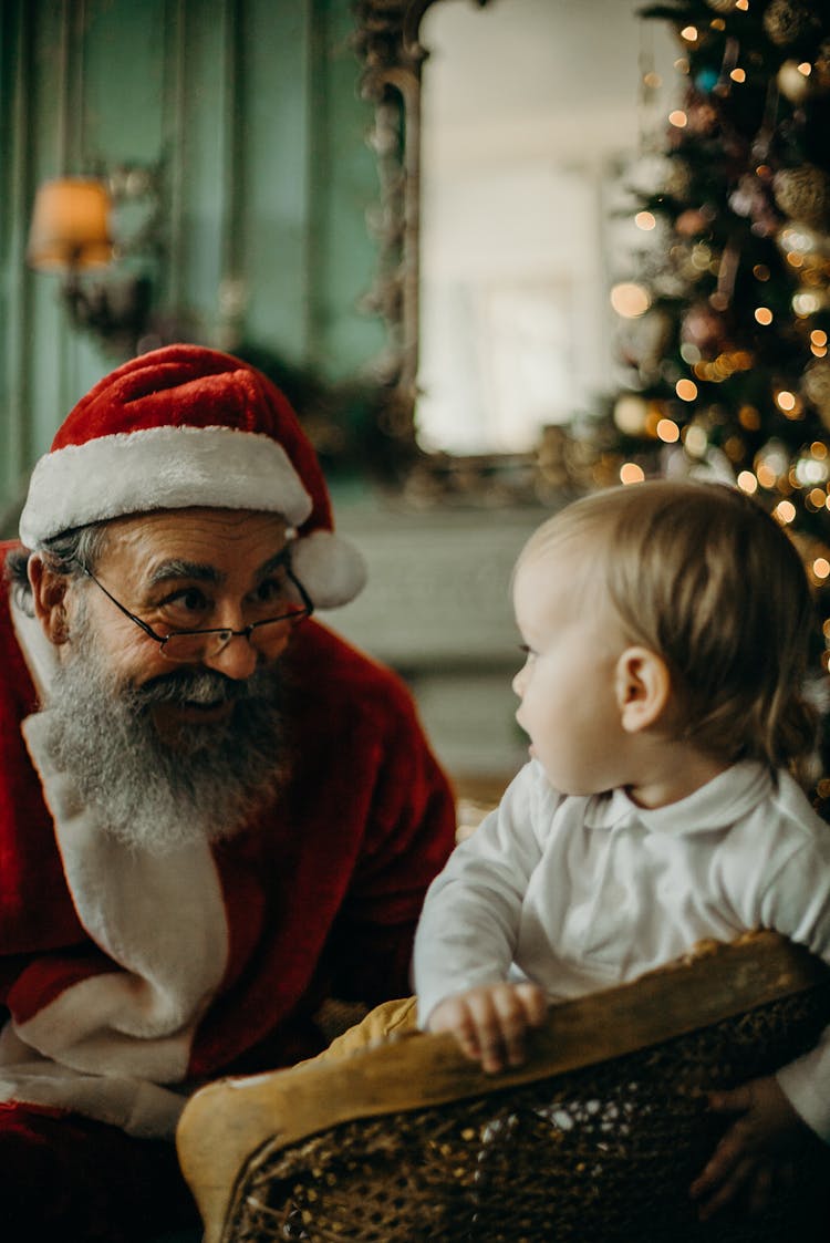 Man In Santa Claus Costume Looking At A Baby