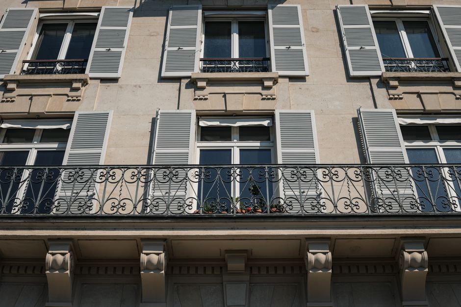 Façade élégante d'un immeuble parisien avec balcon en fer forgé et volets.