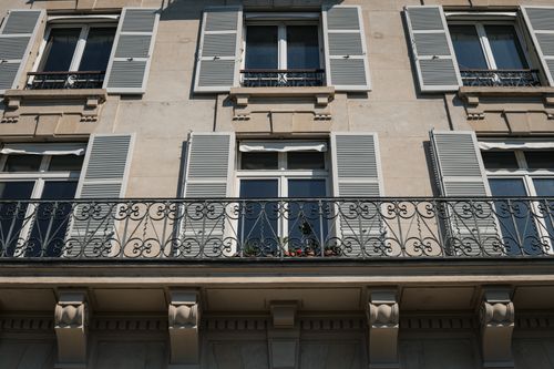 Free Elegant Parisian apartment facade with ornamental iron balcony and shutters in the city of Paris. Stock Photo