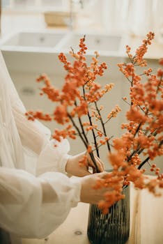 柔和的灯光下，优雅的秋季花卉被布置在室内的现代花瓶中