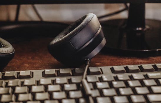 A close-up image of headphones and keyboard on a wooden desk. Ideal for tech and workspace themes.