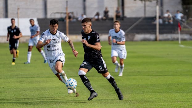 Dynamic moment of players competing in a soccer match on a grassy field outdoors.