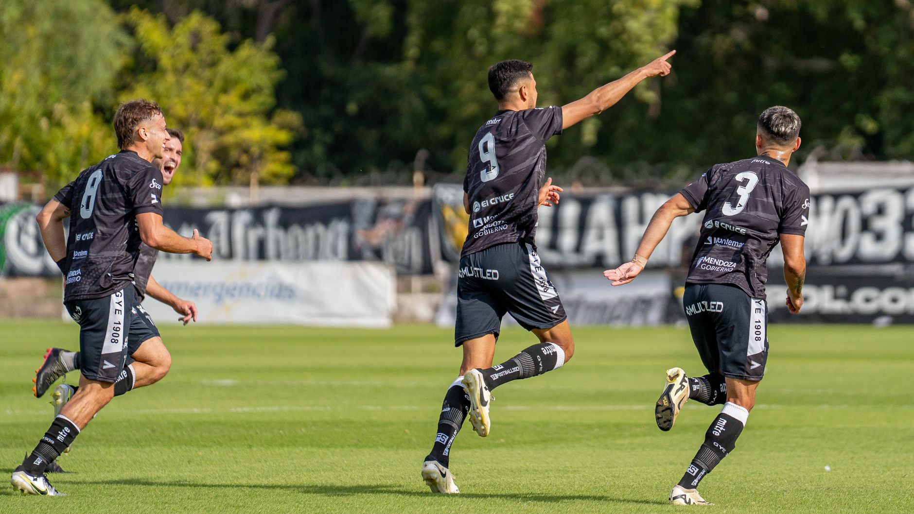 Dynamic shot of soccer players celebrating a goal on a sunny field.