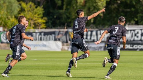 Free Dynamic shot of soccer players celebrating a goal on a sunny field. Stock Photo