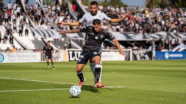 Two soccer players in action during an intense match on a sunny day.