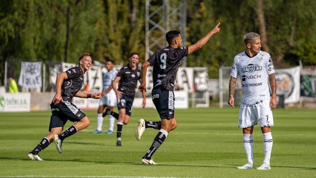 Action-packed soccer match with players celebrating a goal on a sunny day outdoors.