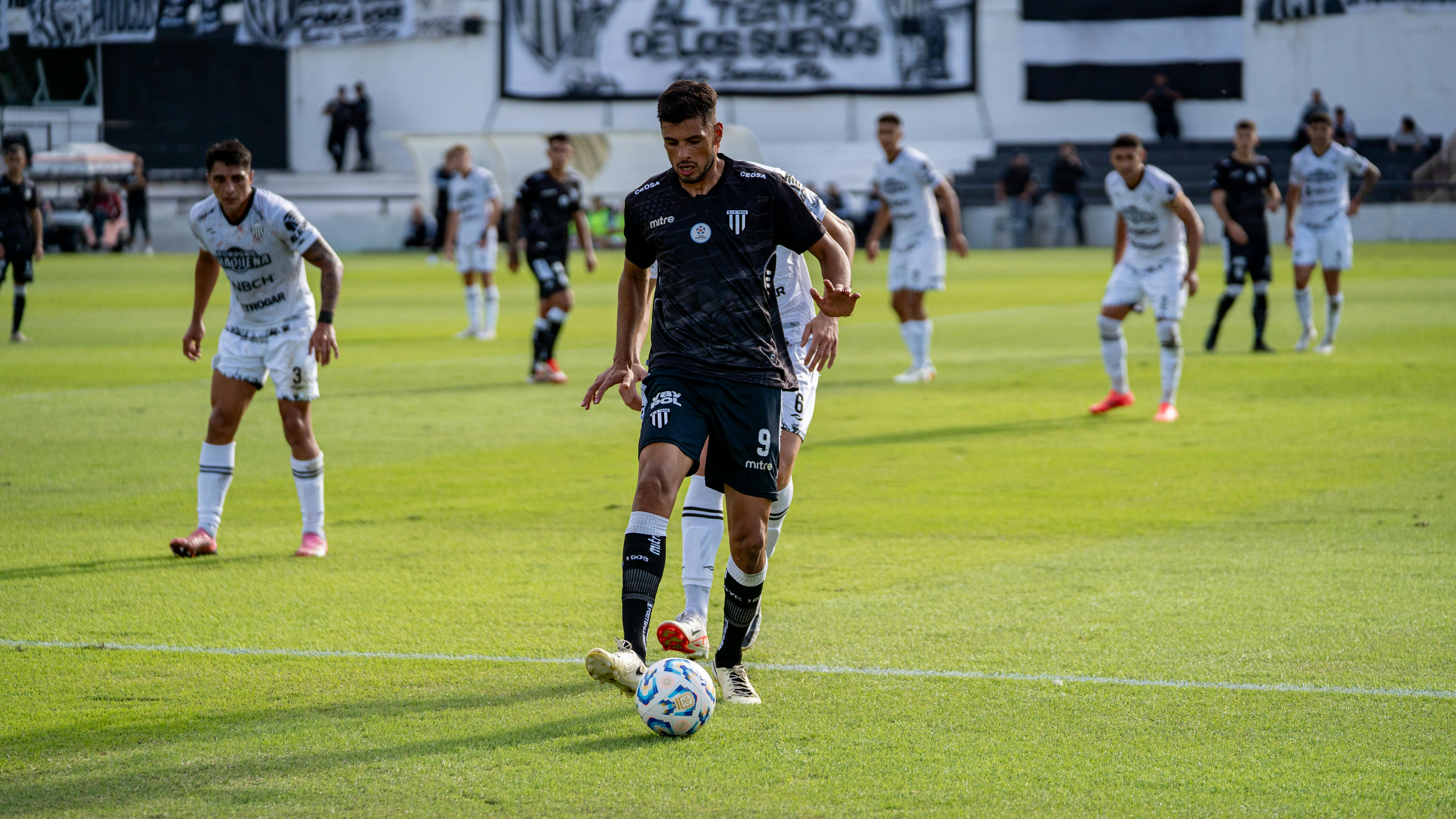 A soccer player controls the ball during an intense outdoor match on a sunny day.